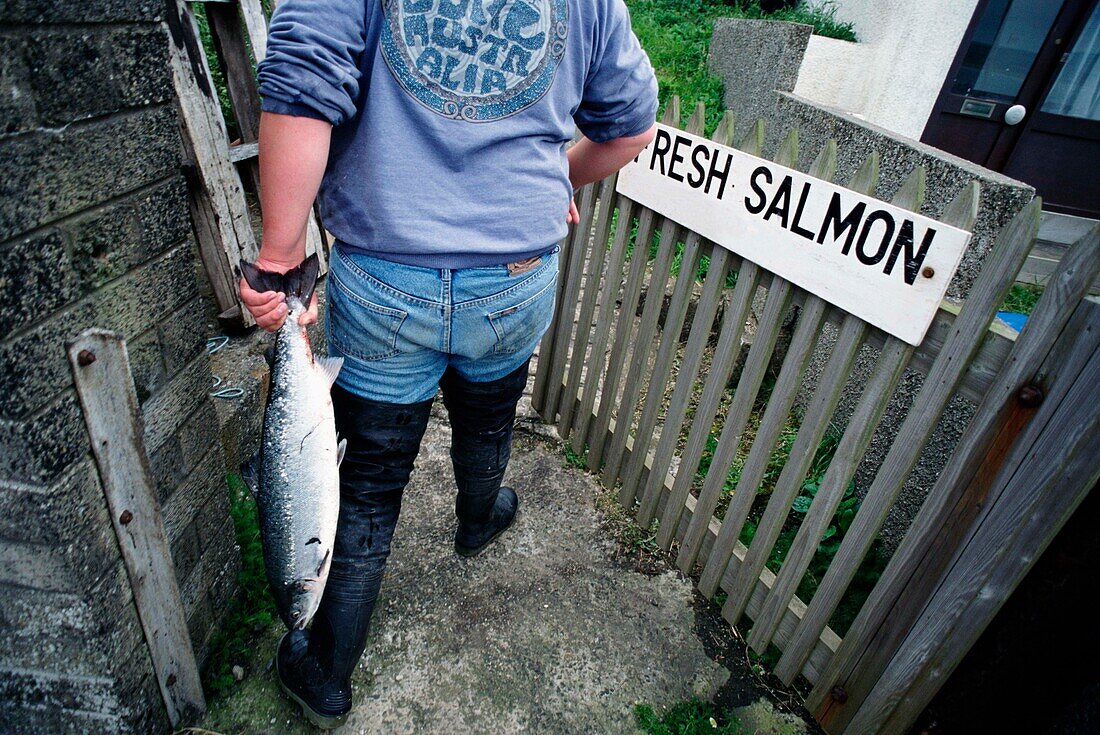 Fisherman Holding Onto A Salmon As He Enters A Gate