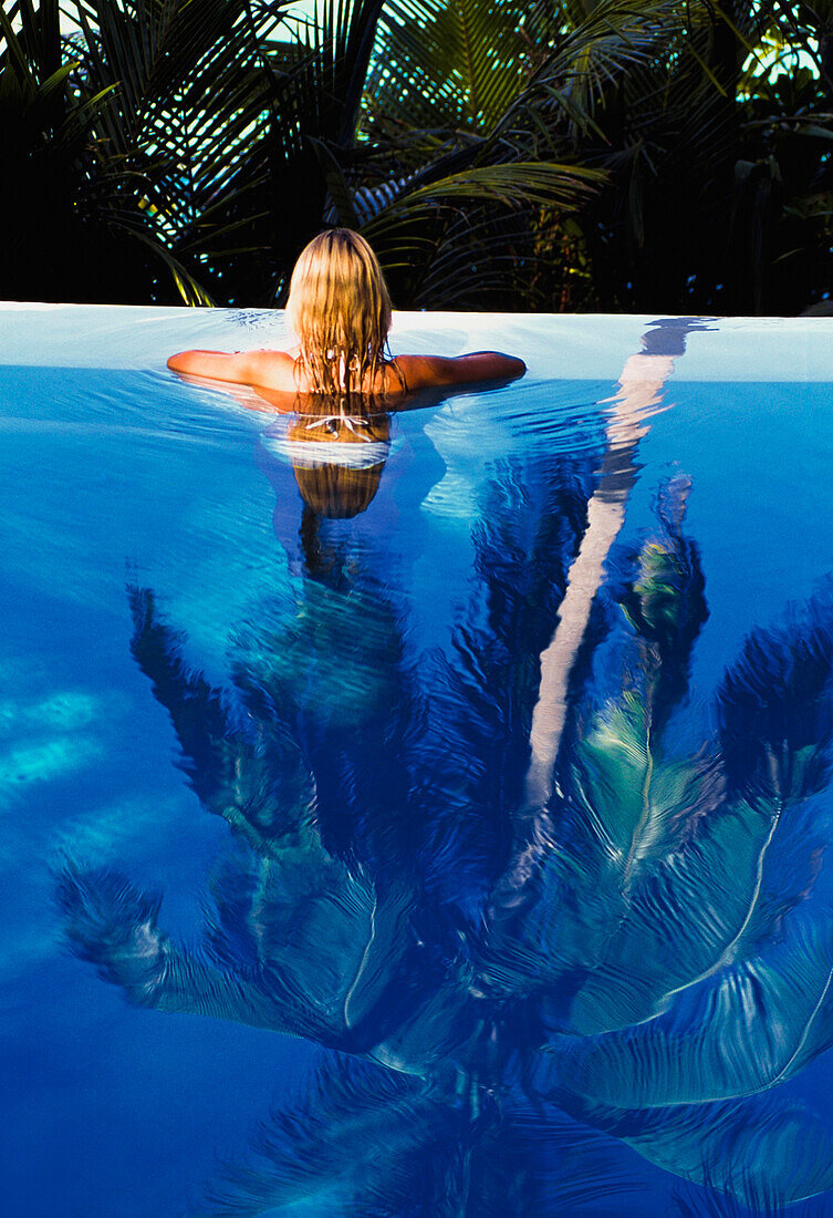 Woman Relaxing In Swimming Poll, Rear View