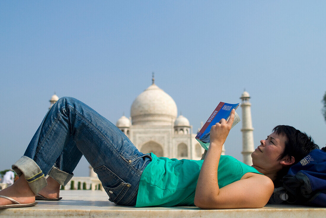 Woman Reading Guide Book In Front Of The Taj Mahal, Side View