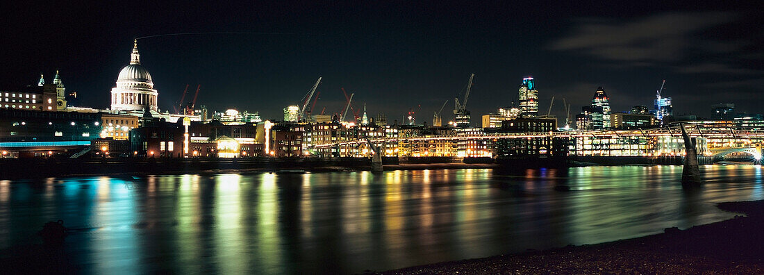Nachtaufnahme der Londoner City von der Southbank aus gesehen, mit der St. Paul's Cathedral auf der linken und der Millennium Bridge auf der rechten Seite.