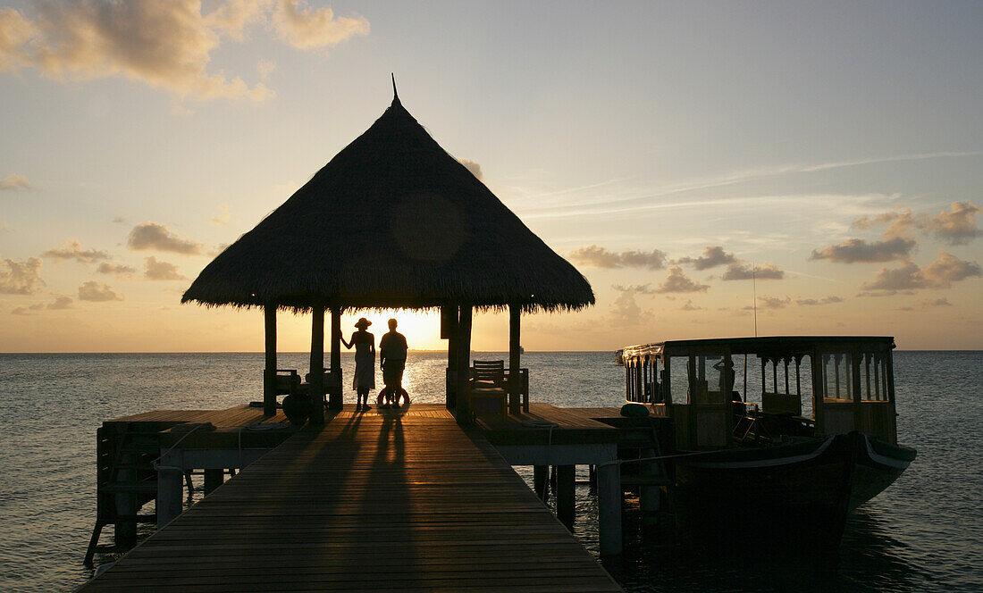 Paar auf Pier beobachten den Sonnenuntergang.