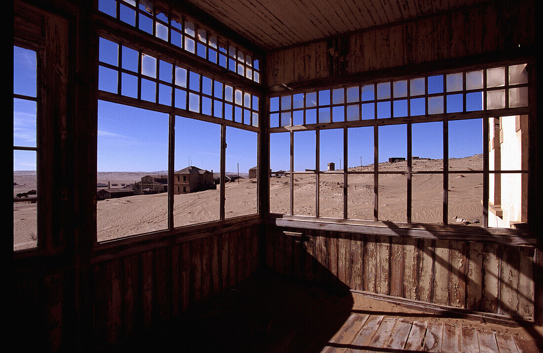 Blick durch Fenster eines stillgelegten Gebäudes in einer Geisterstadt in der Wüste