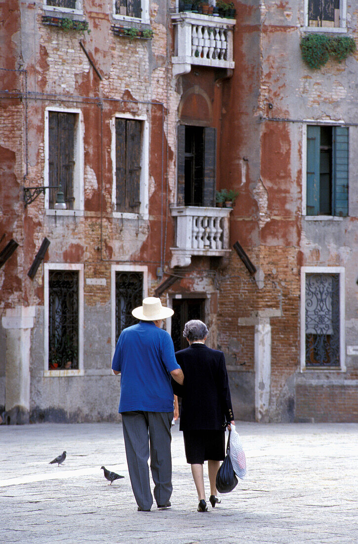Älteres Ehepaar geht in der Nähe von heruntergekommenen Gebäuden spazieren