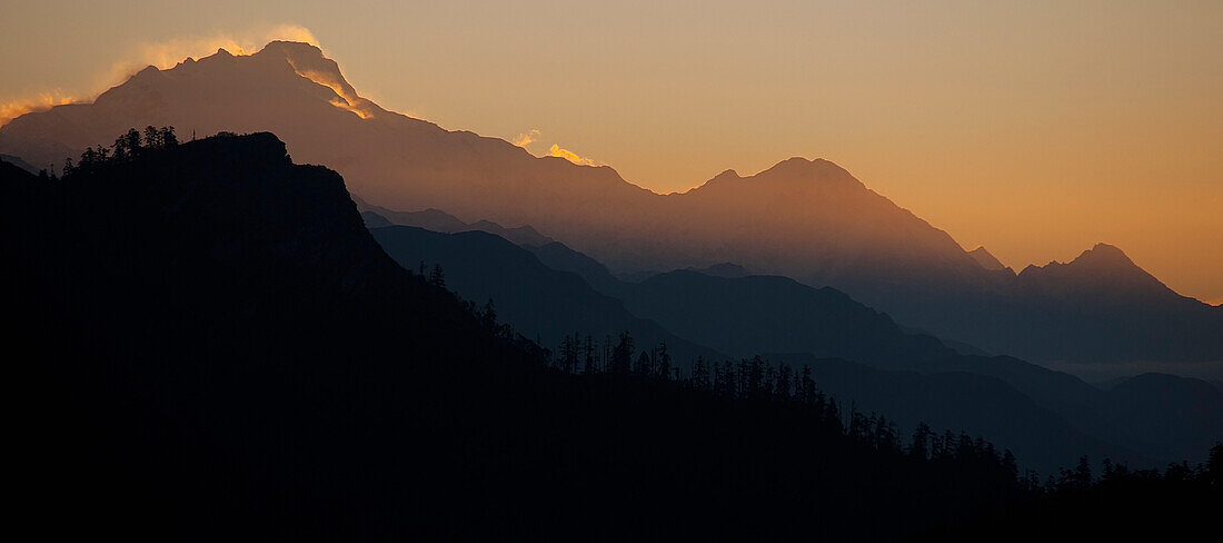 Silhouette einer Berglandschaft mit einem leuchtenden Himmel dahinter bei Sonnenuntergang am Poon Hill; Annapurna Nepal