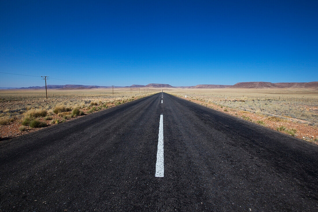 A paved road in a rural area with blue sky; Namibia