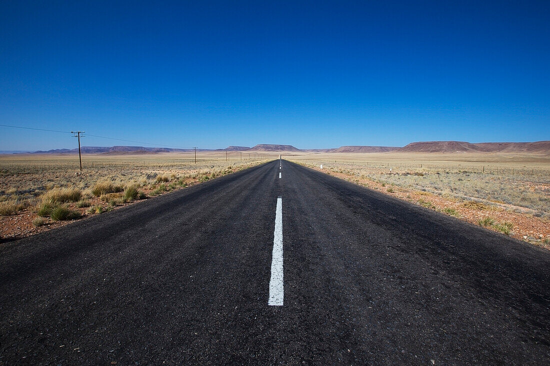 Gepflasterte Straße in einer ländlichen Gegend mit blauem Himmel; Namibia