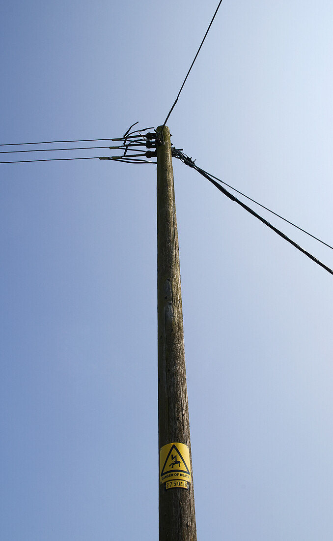 Telefon- und Stromkabel und Pfosten vor blauem Himmel; England