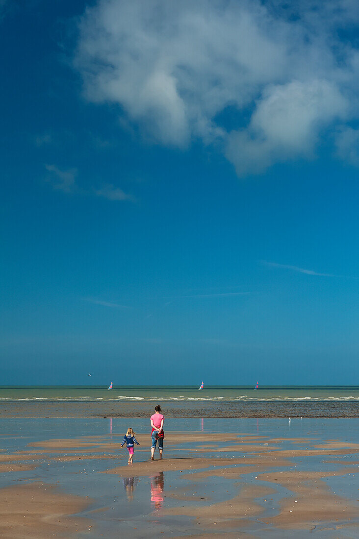 Mutter und kleine Tochter gehen bei Ebbe über den Sandstrand; Granville, Bretagne, Frankreich