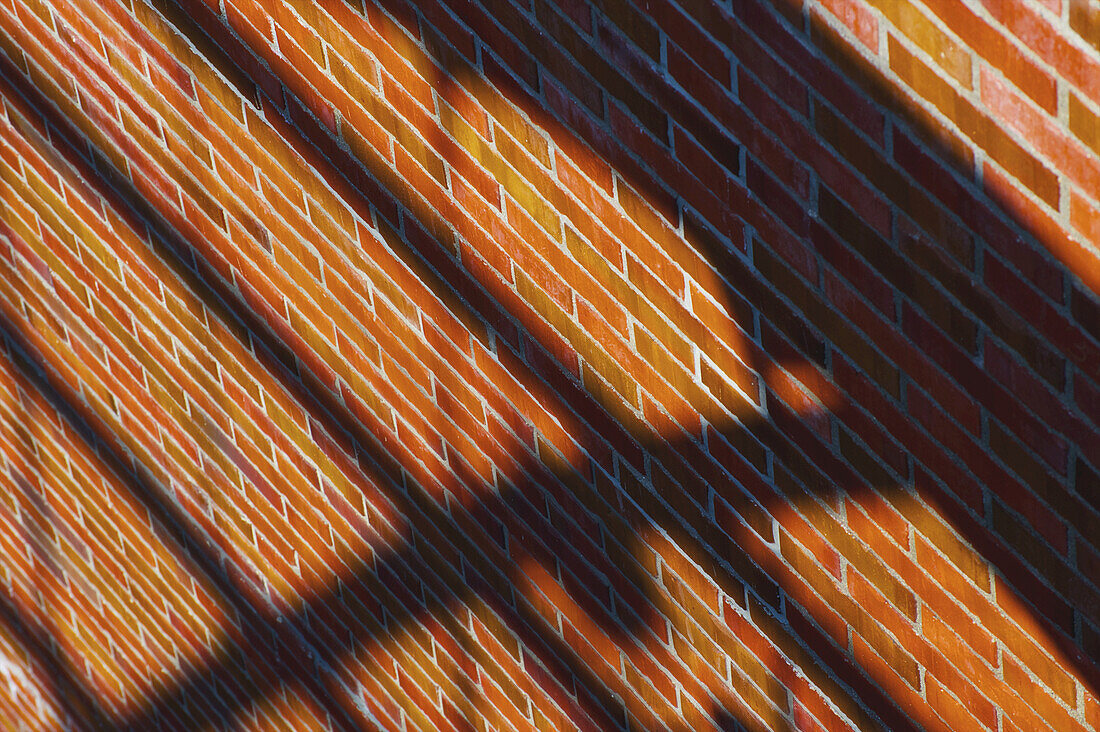 Eine braune Backsteinmauer mit dem Schatten eines Geländers; Hamburg, Deutschland