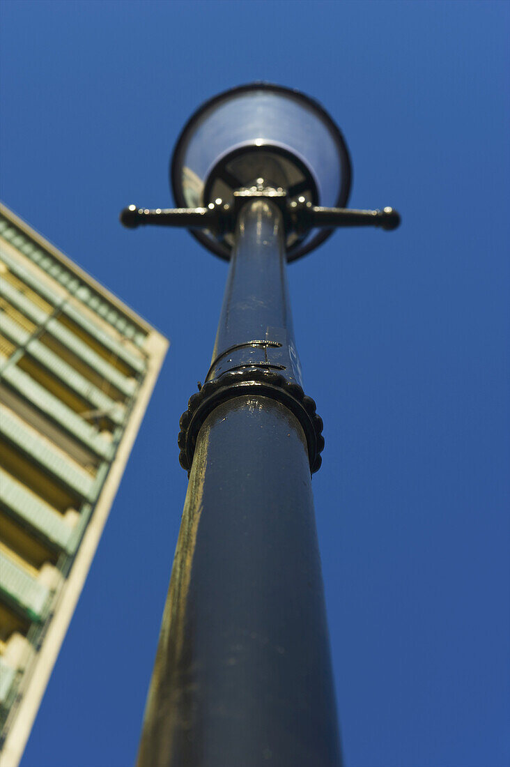 Niedriger Blickwinkel auf einen Laternenpfahl, ein Gebäude und blauen Himmel; London, England