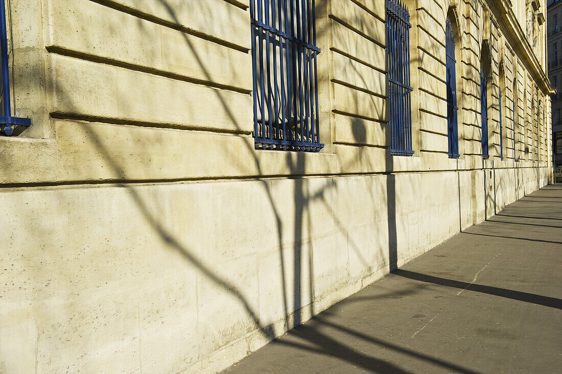 Blaue Gitter an Fenstern entlang eines Gebäudes im historischen Viertel des Marais; Paris, Frankreich