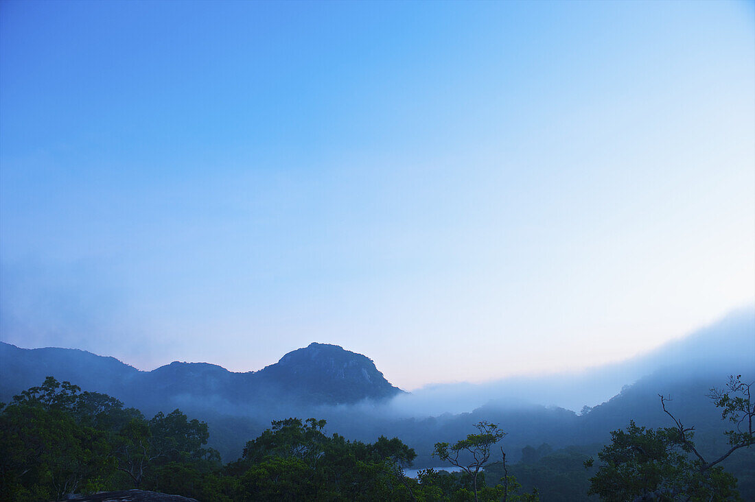 Mountains With Low Cloud Against A Blue Sky At Sunrise; Ulpotha, Embogama, Sri Lanka