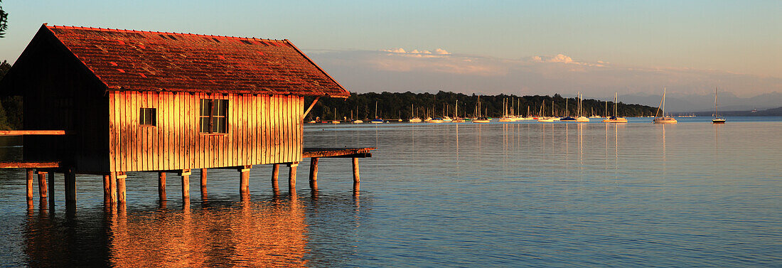 A Building And Boats Moored In The Harbour Of Ammersee At Sunset; Stegen, Bayern, Germany