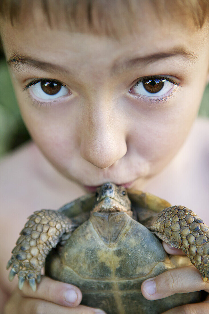 A Young Boy Holding A Kissing A Small Turtle; France