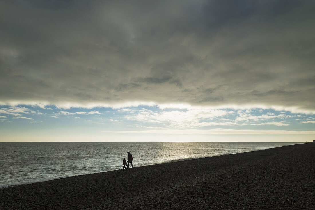 Mutter und Tochter gehen am Strand entlang; Aldeburgh, Suffolk, England