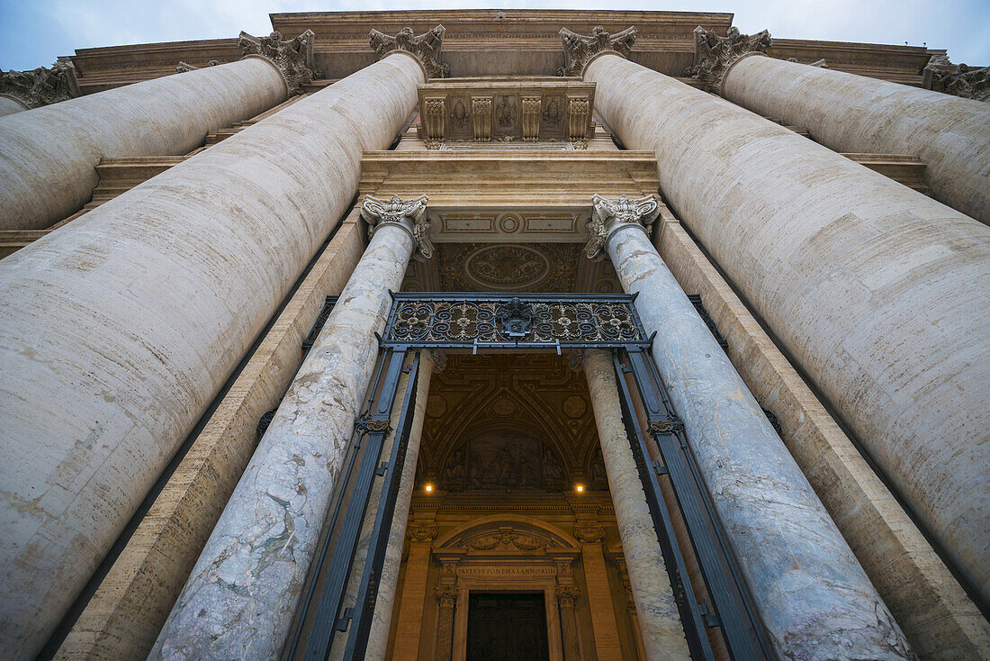 Low Angle View Of St. Peter's Basilica With Large Columns Around A Doorway; Rome, Lazio, Italy