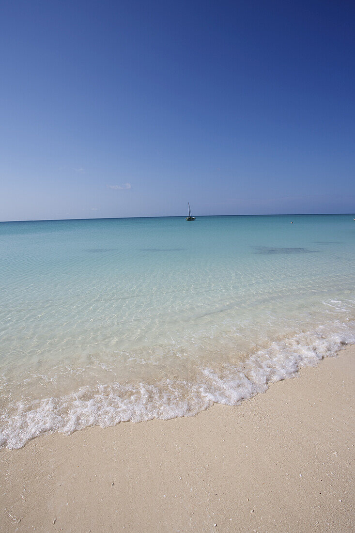 Weißer Sandstrand und ein Segelboot im Indischen Ozean; Vamizi Island, Mosambik