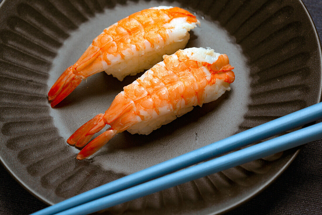 Prawns and rice on a blue dish with chopsticks. 