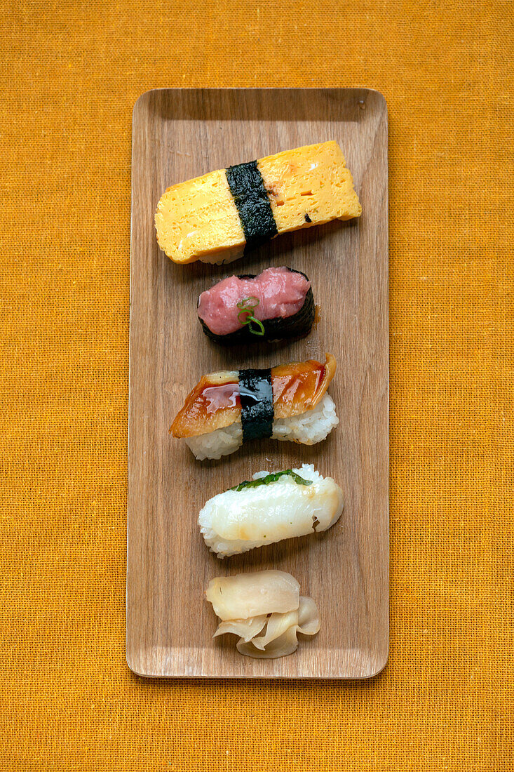 Sushi-Platte, eine Auswahl an rohem Fisch und Reissnacks mit Essstäbchen. 