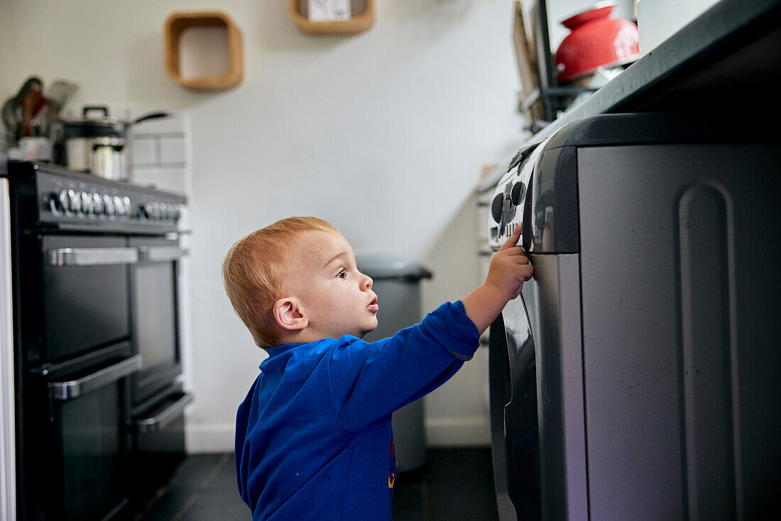 Kleinkind greift nach oben und berührt ein Gerät in der Küche