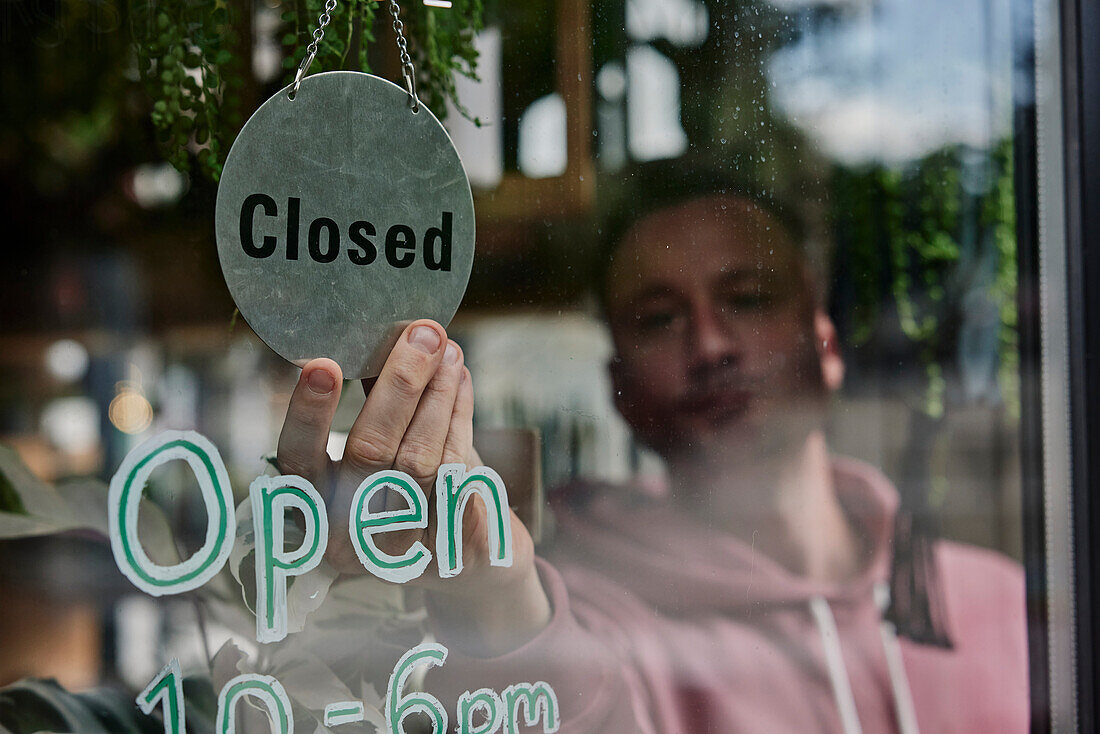 Mann platziert Schild "Geschlossen" im Schaufenster eines Geschäfts