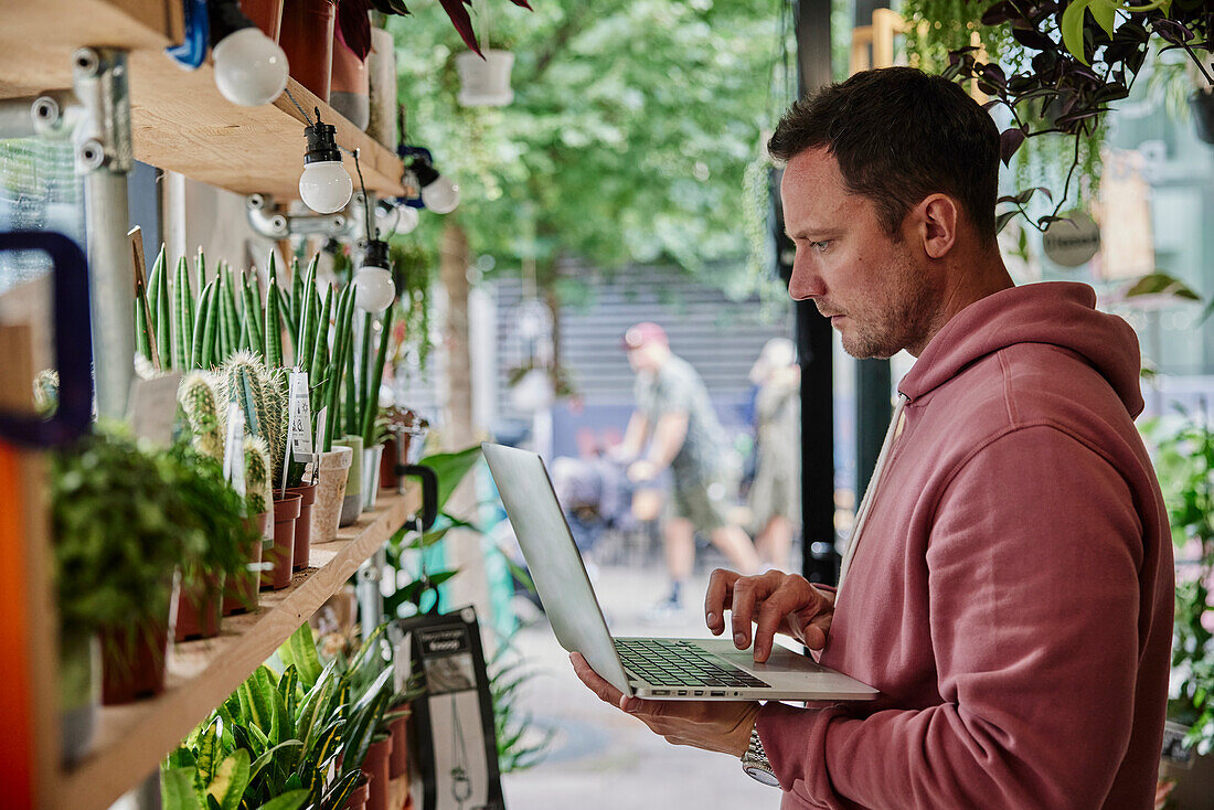 Mann macht Bestandsaufnahme mit Laptop in einem Blumenladen