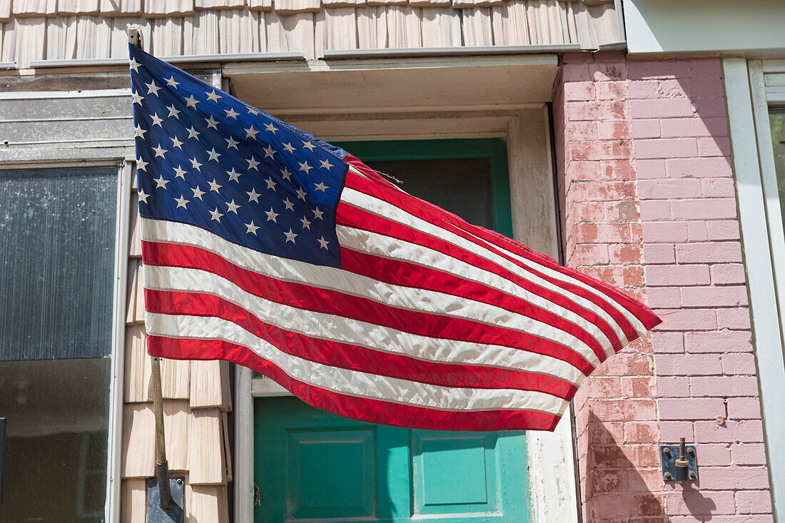 Amerikanische Flagge vor einem Gebäude, einem Schaufenster auf der Hauptstraße. 