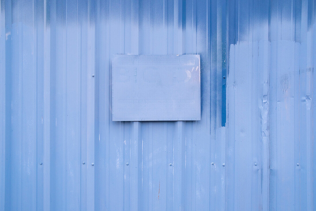 A painted sign on painted blue building wall.