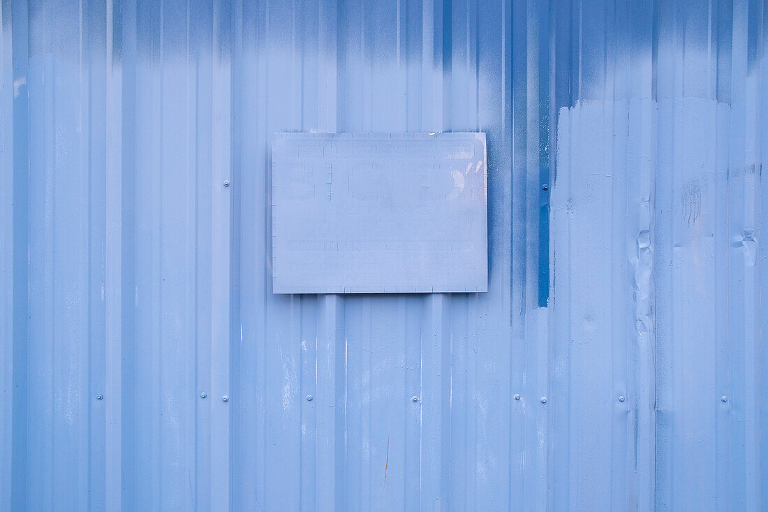 Ein gemaltes Schild auf einer blau gestrichenen Hauswand.