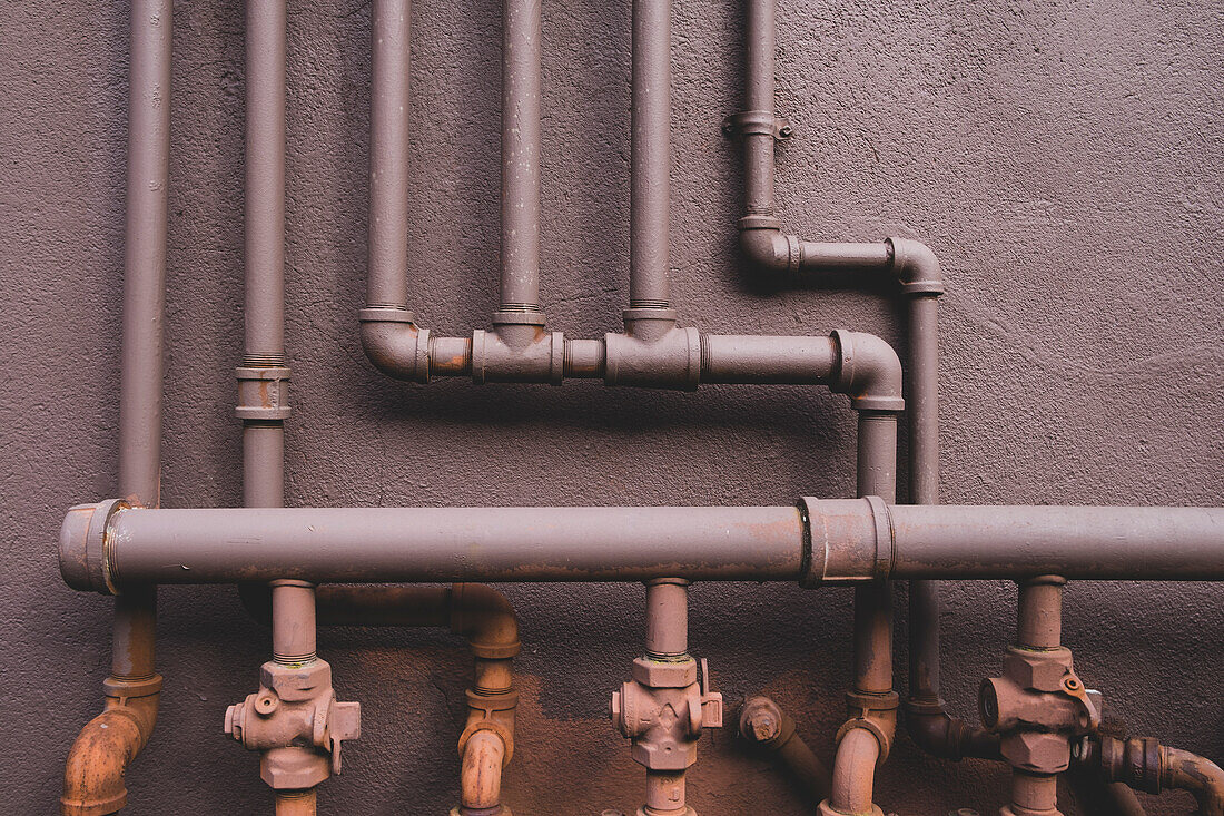 Entlang einer braunen Wand verlaufende Erdgasversorgungsrohre, Ventile und Verbindungen.
