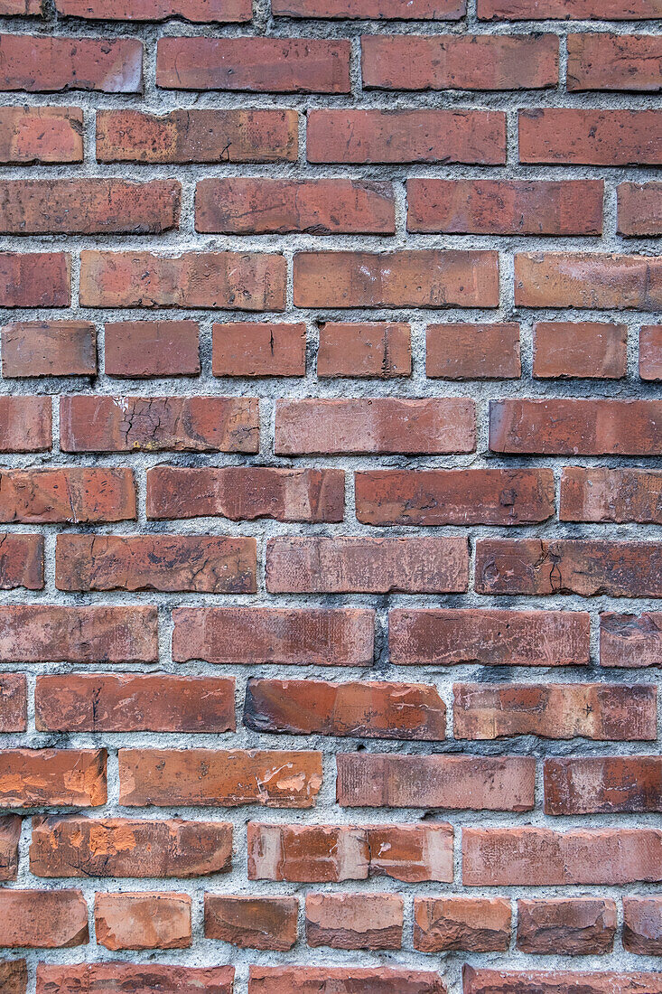 Eine Ziegelmauer, rote Tonziegel, die in einem regelmäßigen Muster zu einer Mauer verlegt sind. 