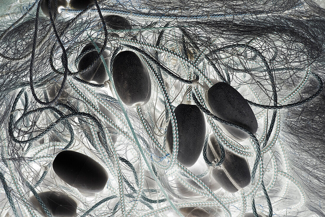 Ein Stapel kommerzieller Fischernetze, Seile und Schwimmer, monochromes Bild. 