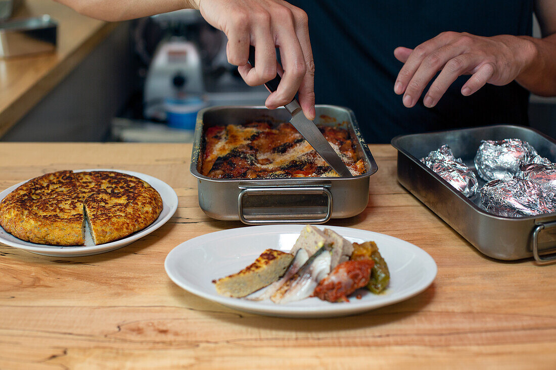 A man preparing food dishes, plates of Italian food on a restaurant kitchen counter. 