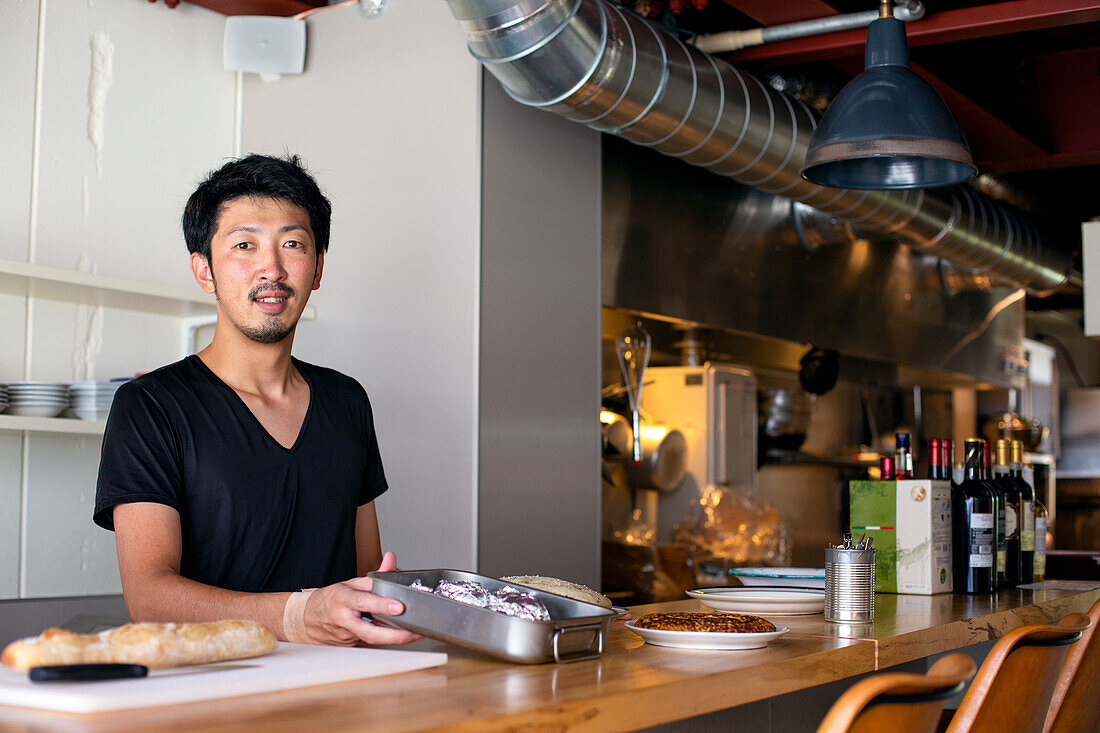 A chef working in a restaurant, at the pass preparing plates of food for service, 