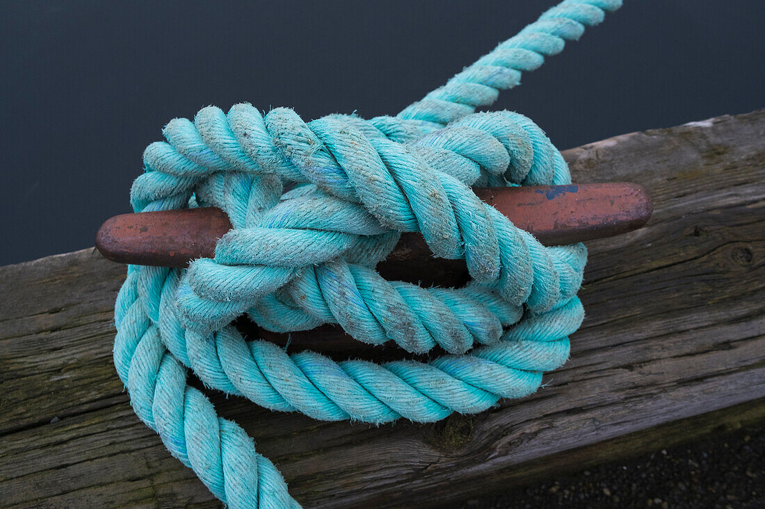 Industrielle Seile, die um eine metallene Bootsklampe gebunden sind.