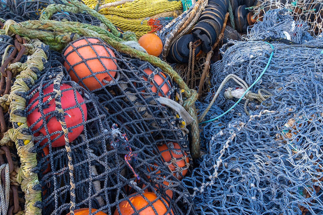 Ein Stapel kommerzieller Fischernetze mit Seilen und Schwimmern.
