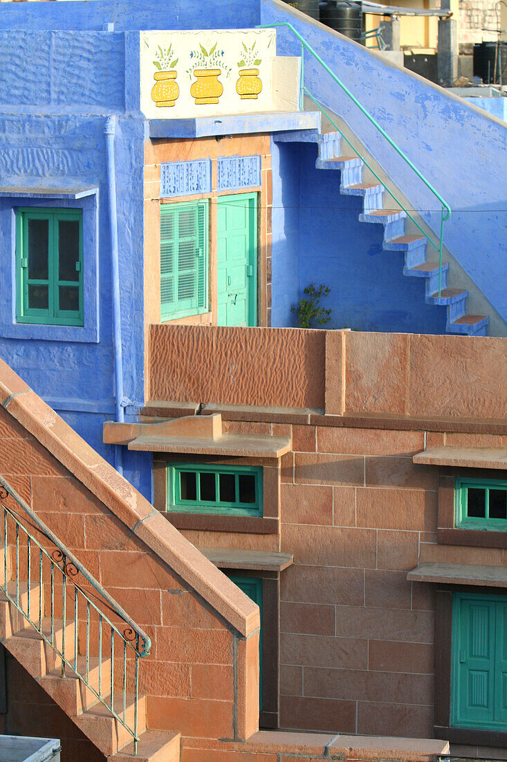 Blue City, Jodhpur, India. Blue apartment with a teal, green door, and painted flower pots, and a brick stairwell