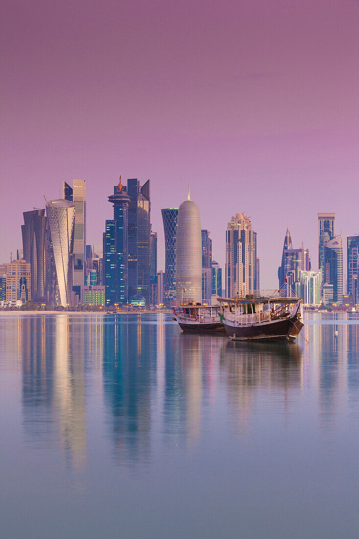 Katar, Doha, Dhows in der Bucht von Doha mit Wolkenkratzern in der Westbucht, Dämmerung