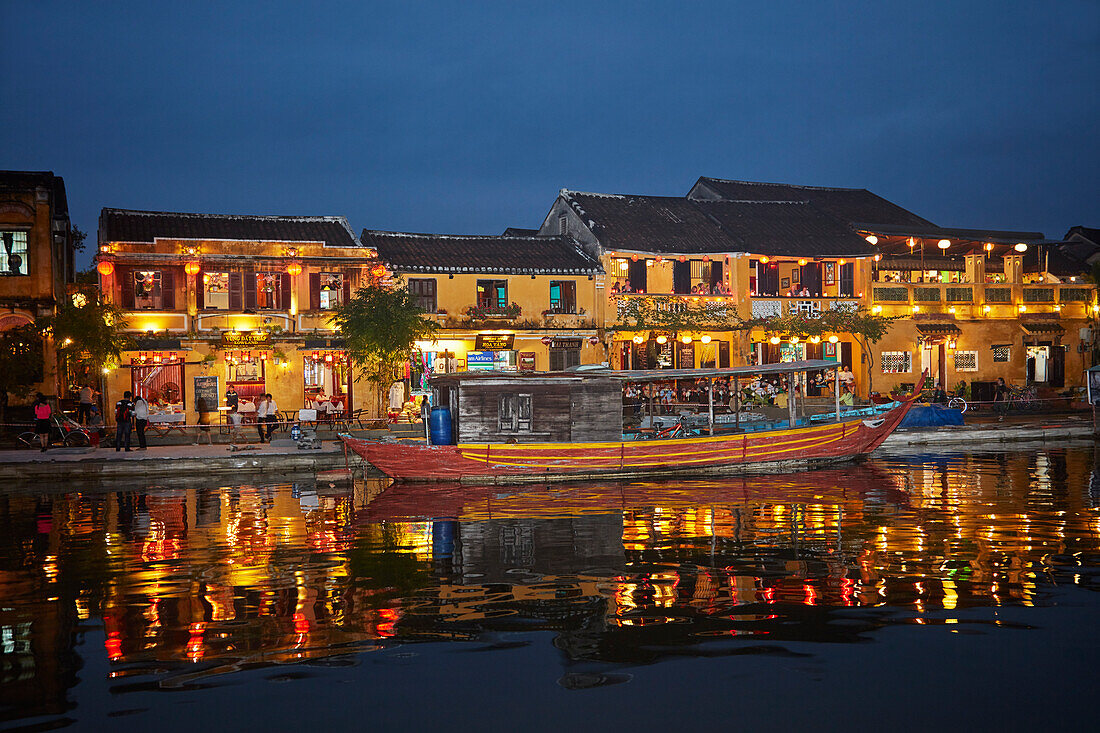 Boat and restaurants reflected in Thu Bon River at dusk, Hoi An (UNESCO World Heritage Site), Vietnam