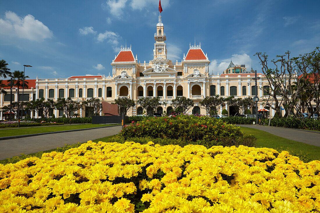 Blumen und historisches Gebäude des Volkskomitees (ehemaliges Hotel de Ville de Saigon), Ho-Chi-Minh-Stadt (Saigon), Vietnam