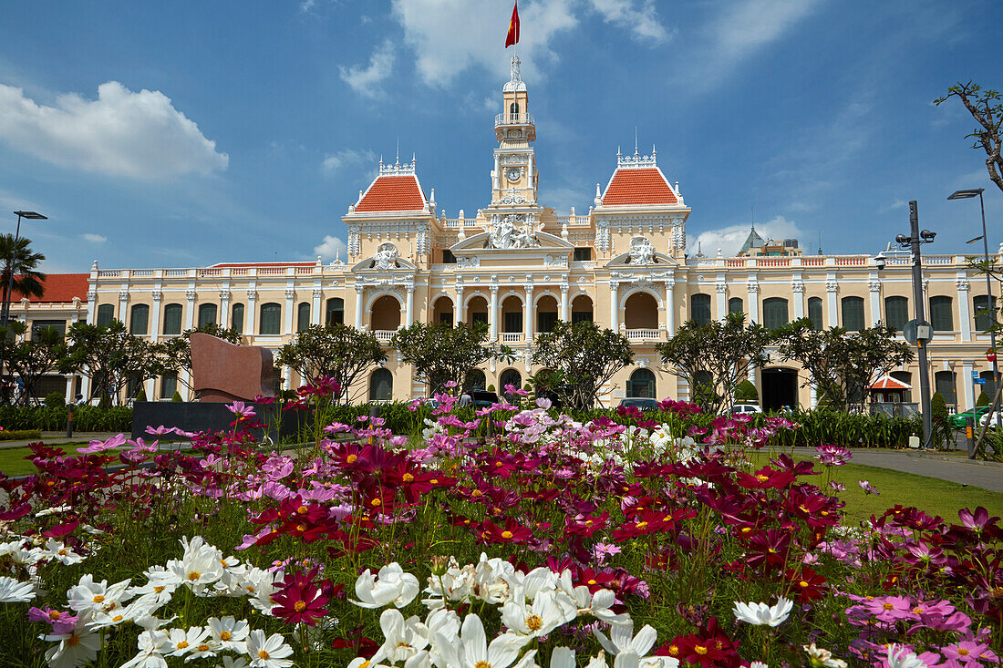 Blumen und historisches Gebäude des Volkskomitees (ehemaliges Hotel de Ville de Saigon), Ho-Chi-Minh-Stadt (Saigon), Vietnam