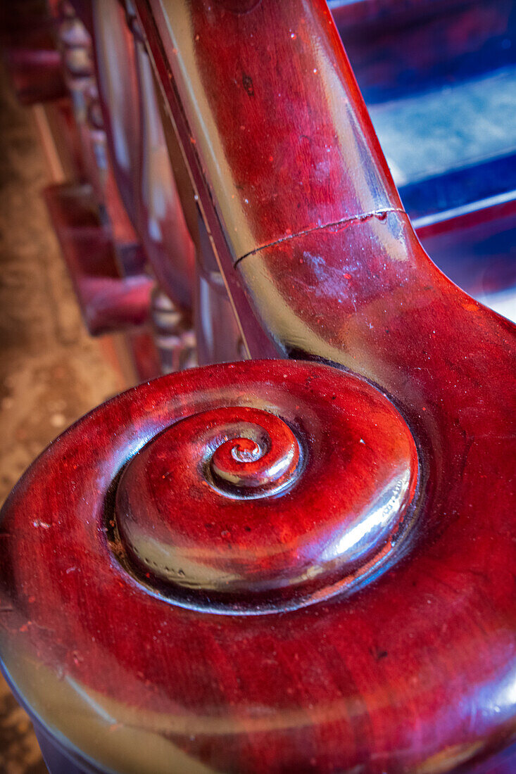 Snail shell-like curve on red wooden bannister handrail in Trinidad, Cuba
