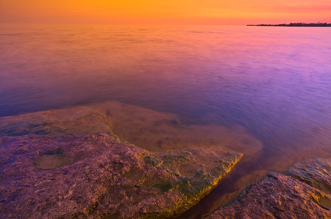 Canada, Ontario, Selkirk. Morning light on rocky shoreline of Lake Erie