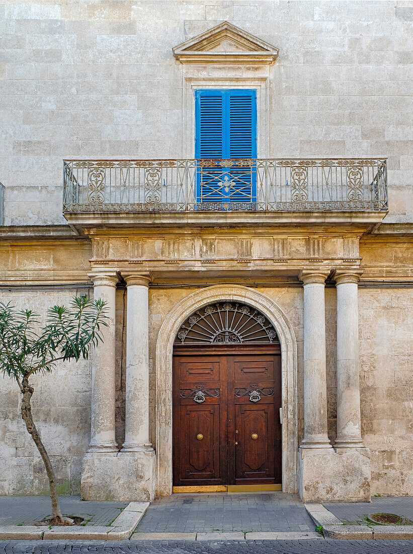 Italien, Apulien, Brindisi, Itria-Tal, Ostuni. Schöne Holztür mit Balkon darüber und blauen Fensterläden.