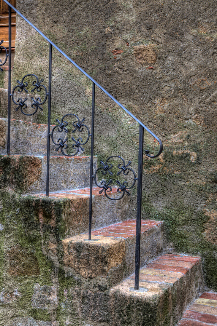 Italien, Toskana, Pienza. Eine Treppe mit schmiedeeisernem Geländer führt zum Eingang eines Hauses in Pienza.