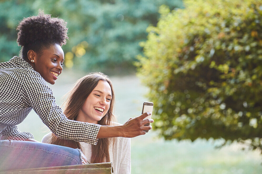 Smiling young friends talking selfie on smartphone