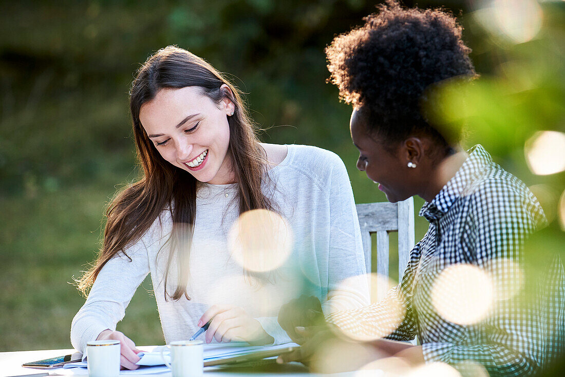 Smiling young friends studying at table in park