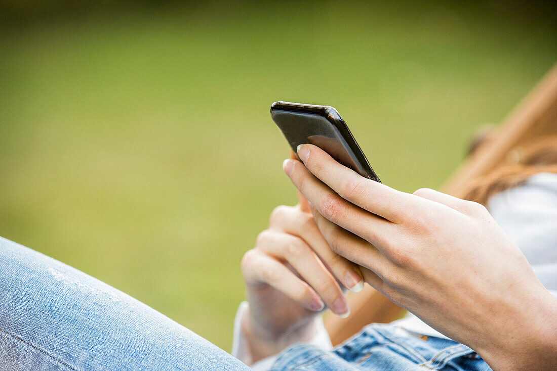 Mid section of young woman using smartphone in park