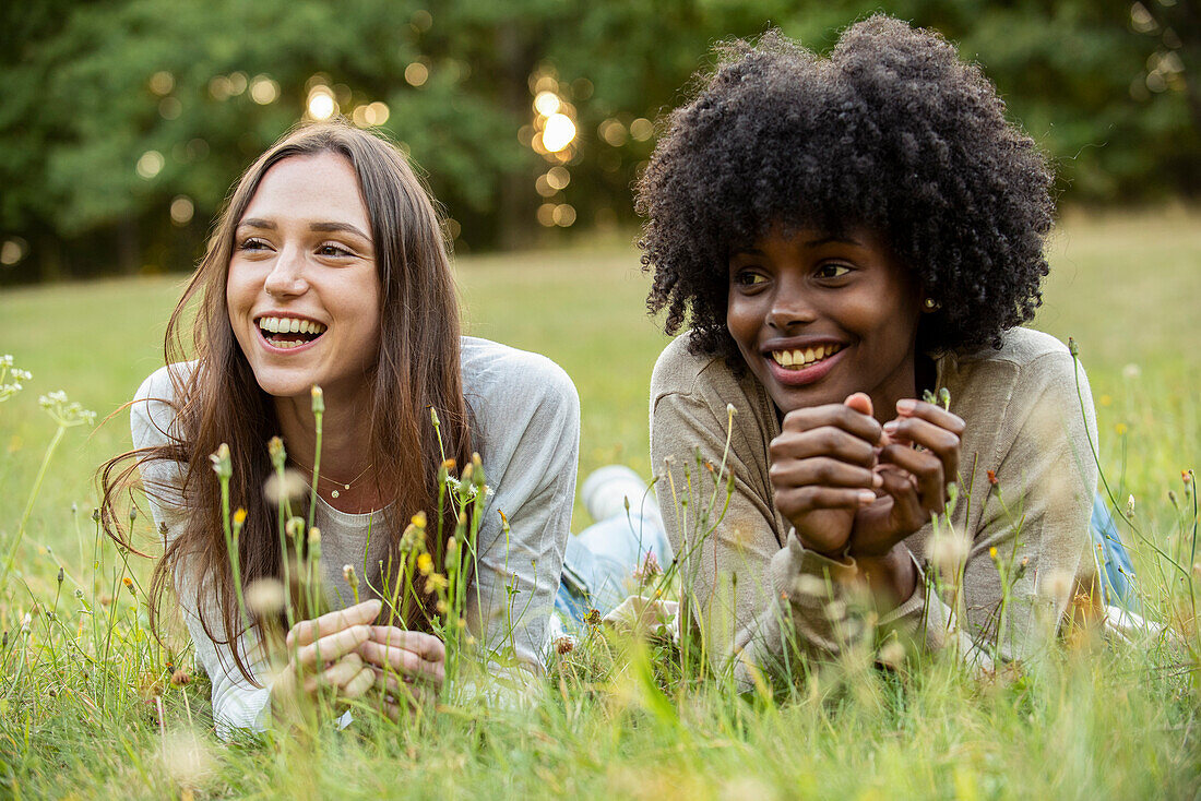 Lächelnde junge Freundinnen liegend im Park