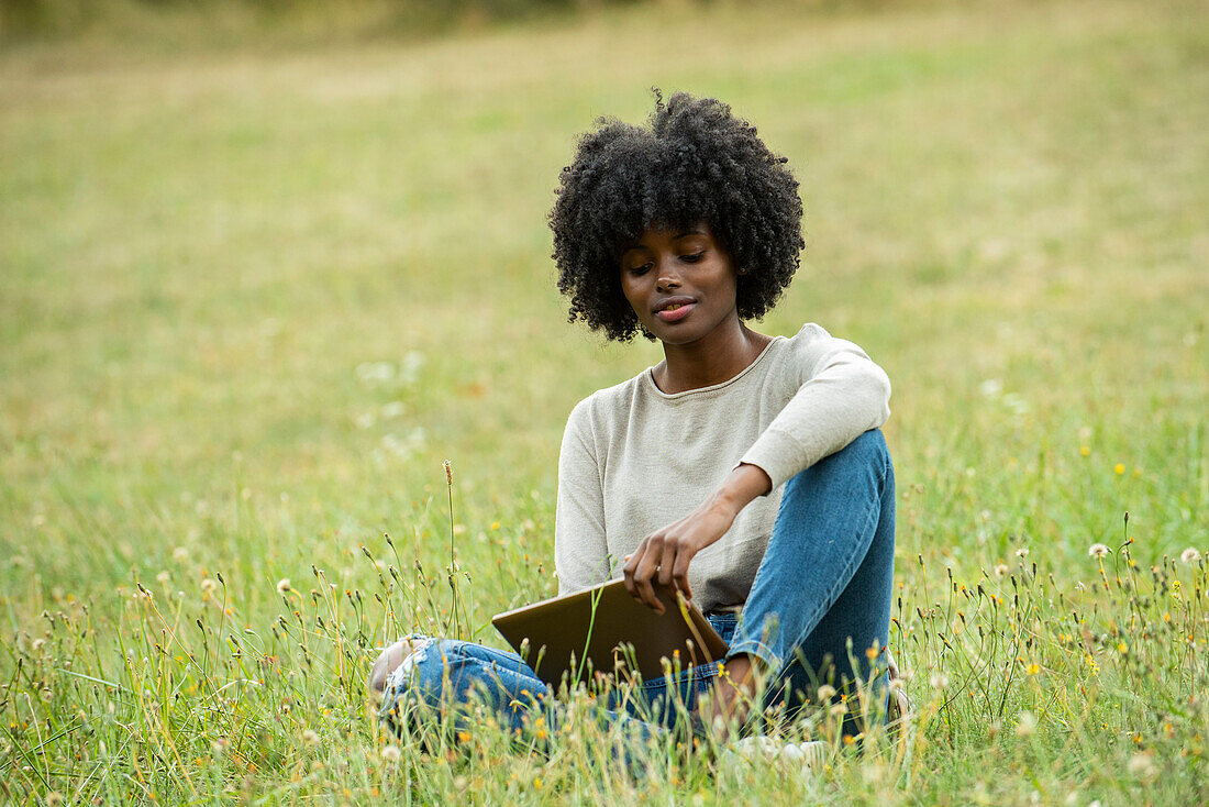 Young woman using digital tablet in public park